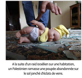 A la suite d’un raid aérien israélien, un Palestinien dans une maison ramasse une poupée qui se trouve sur le sol jonché de débris de verre. (AFP/Getty)